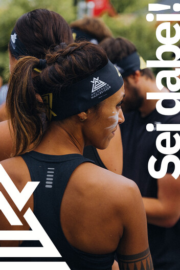 Zur Anmeldung Teilnehmerin von hinten abgebildet steht fokussiert am Start. Arlberger Wadlbeisser Logo als Designelement in weiß am linken Bildrand und Schriftzug "Sei dabei!" am rechten Bildrand.