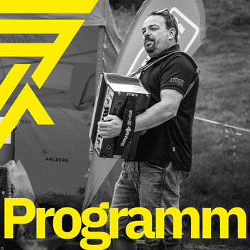 Zum Rahmenprogramm Musikant spielt die Ziehorgel an einer Labestation in Lederhose. Arlberger Wadlbeisser Logo als Designelement in gelb am linken Bildrand und Schriftzug "Programm" am unteren Bildrand. Bild in Graustufen.